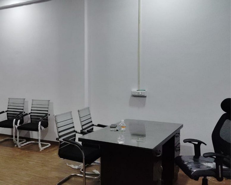 Office space with a desk and several chairs against a white wall.