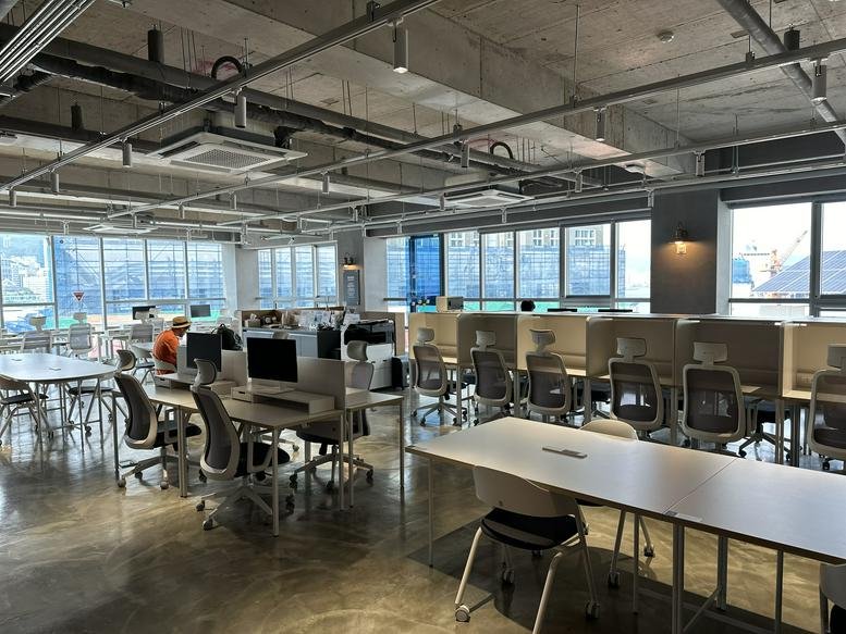Spacious open-plan workspace at The Hyuil Busan, featuring multiple desk banks and panoramic city views.