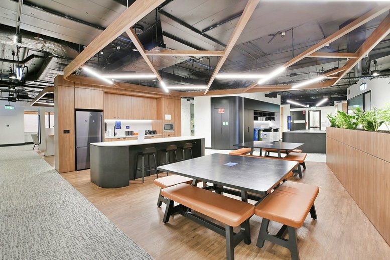 Spacious communal dining area with black tables and bench seating.