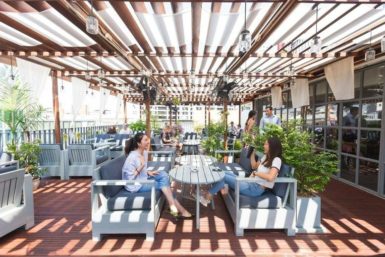 Spacious outdoor terrace at The Hive Thonglor featuring lounge seating and a slatted pergola roof.