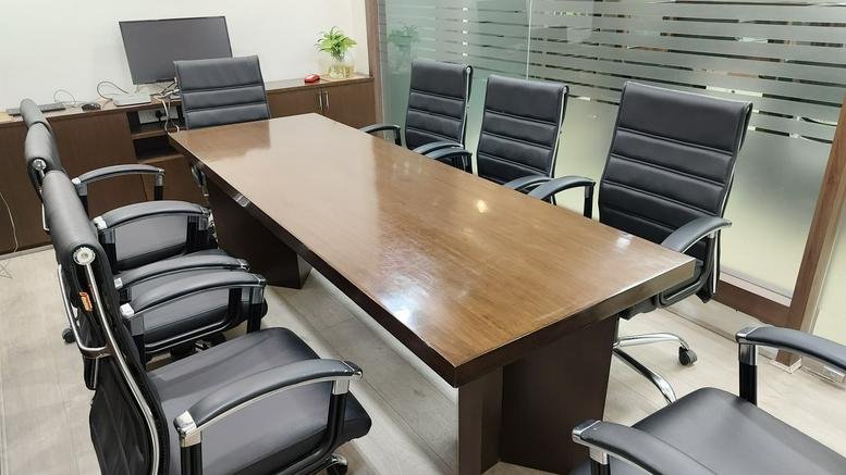 Professional meeting room at Spaze I Tech Park featuring a large wooden table and black leather chairs.