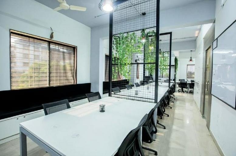 Meeting area at Waman Ganesh Heights with long white tables and mesh dividers.