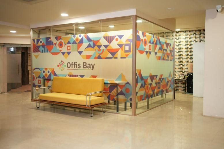 Bright reception area of Hamid Building with a yellow sofa and geometric patterned glass walls.