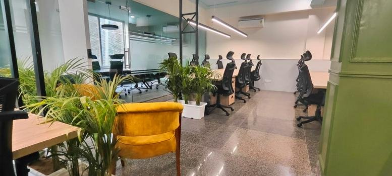 Spacious interior of ZO Space, 252, Saket featuring an open workspace with lush plants and a yellow velvet chair.