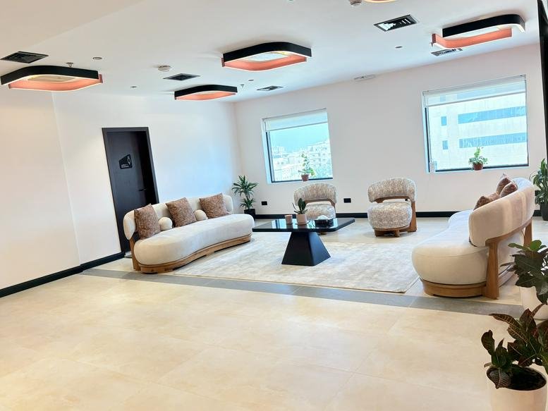 Spacious communal lounge at Dar Rayhan by Rotana with curved white sofas and designer lighting.