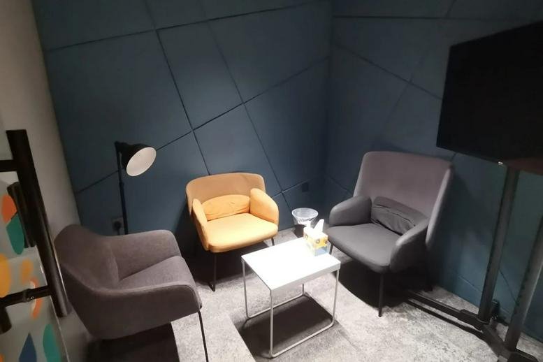 A colorful meeting room at Dan Plaza, Makkah with a feature wall and plush yellow and grey armchairs.