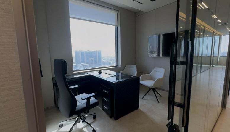 Modern workspace at Dar Rayhan by Rotana featuring a sleek black desk and panoramic city views.