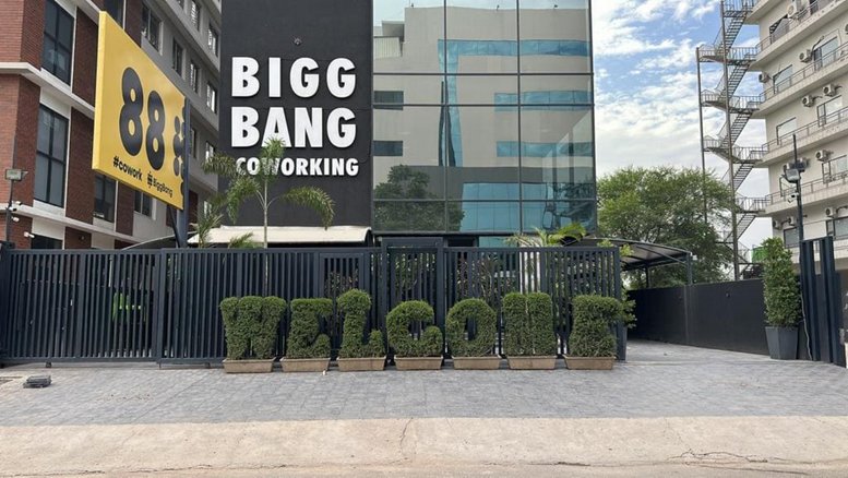 Exterior view of the Bigg Bang Coworking building with a large welcome sign made of hedges.