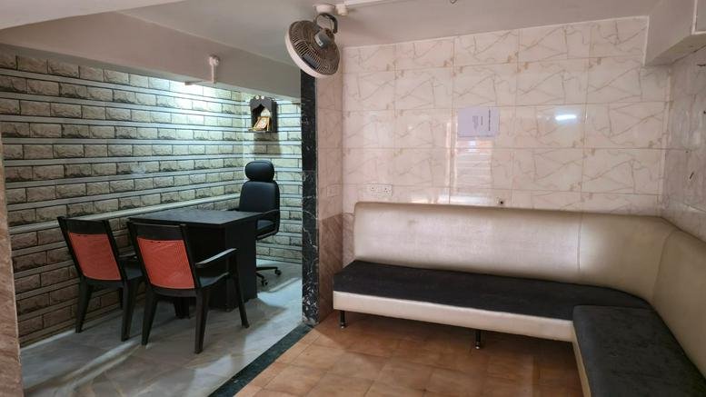Spacious waiting area featuring a long L-shaped banquette sofa and an adjacent private office space.