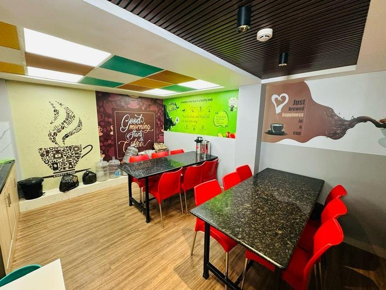 Vibrant communal dining area and café with red chairs and coffee-themed wall art.