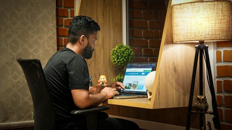 Person working at a laptop in a home office with warm lighting.