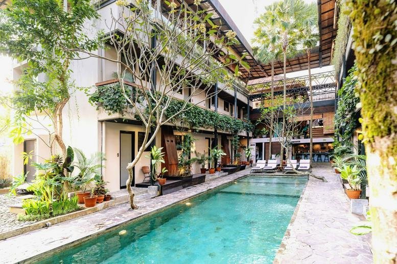Exterior view of the multi-level Jalan Penestanan building featuring lush greenery and a swimming pool.