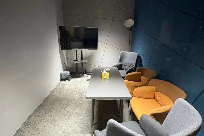 Meeting room at King Abdul Aziz Branch Road with a long table, orange armchairs, and a wall-mounted TV.