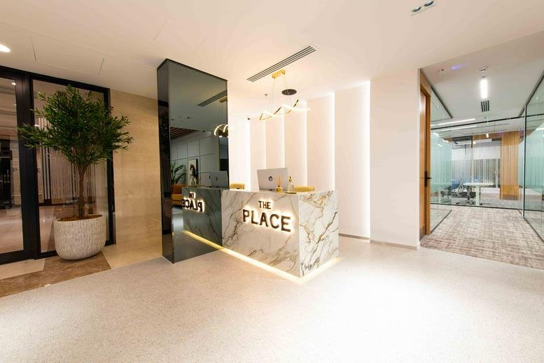 Modern reception desk at King Fahd Road with marble finishes, backlit signage, and a tall mirrored partition.