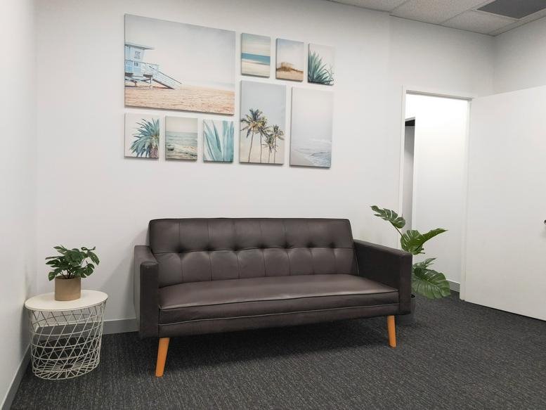 Reception area at 38/207 Currumburra Road featuring a brown sofa, wall art, and indoor plants.