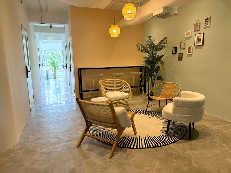 Warm lounge area with wicker seating, pendant lights, and a feature wall with framed art.