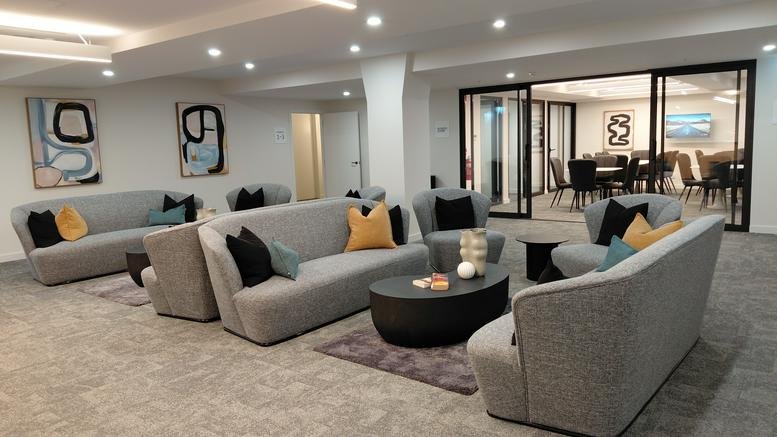 Spacious communal lounge with grey sofas and abstract art at Level1/233, Collins Street.