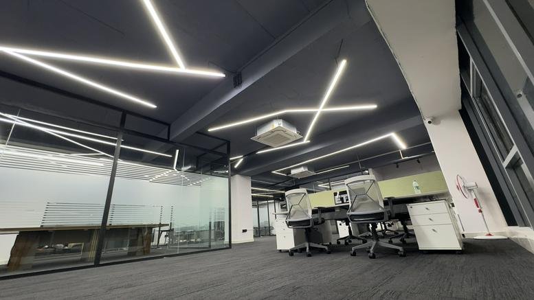 Spacious open-plan workspace at Marrichettu Road with modern linear ceiling lights and glass partitions.