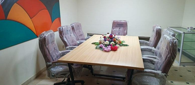 Professional meeting room at Muslim Town, Muslim town Dadabhoy Town, Karachi with a wooden table and colorful wall art.