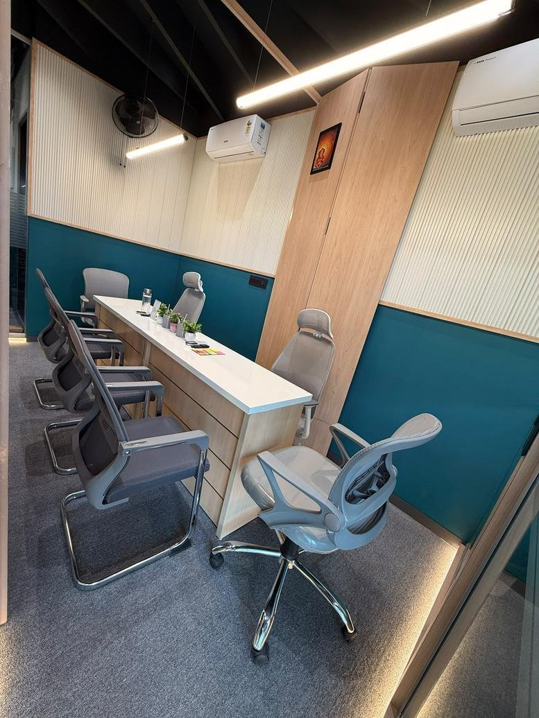 Wide-angle view of a professional meeting space with teal accents and linear lighting.