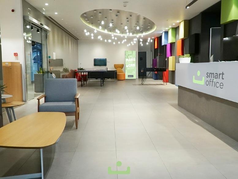 Spacious reception lounge with a branded smart office desk and colorful decor.