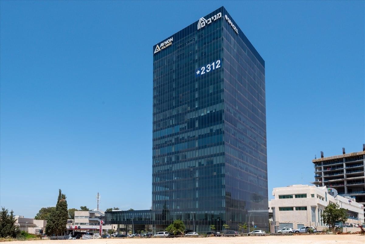 Exterior view of the glass-facade 1 Hatachana St Kfar Saba building under a clear blue sky.