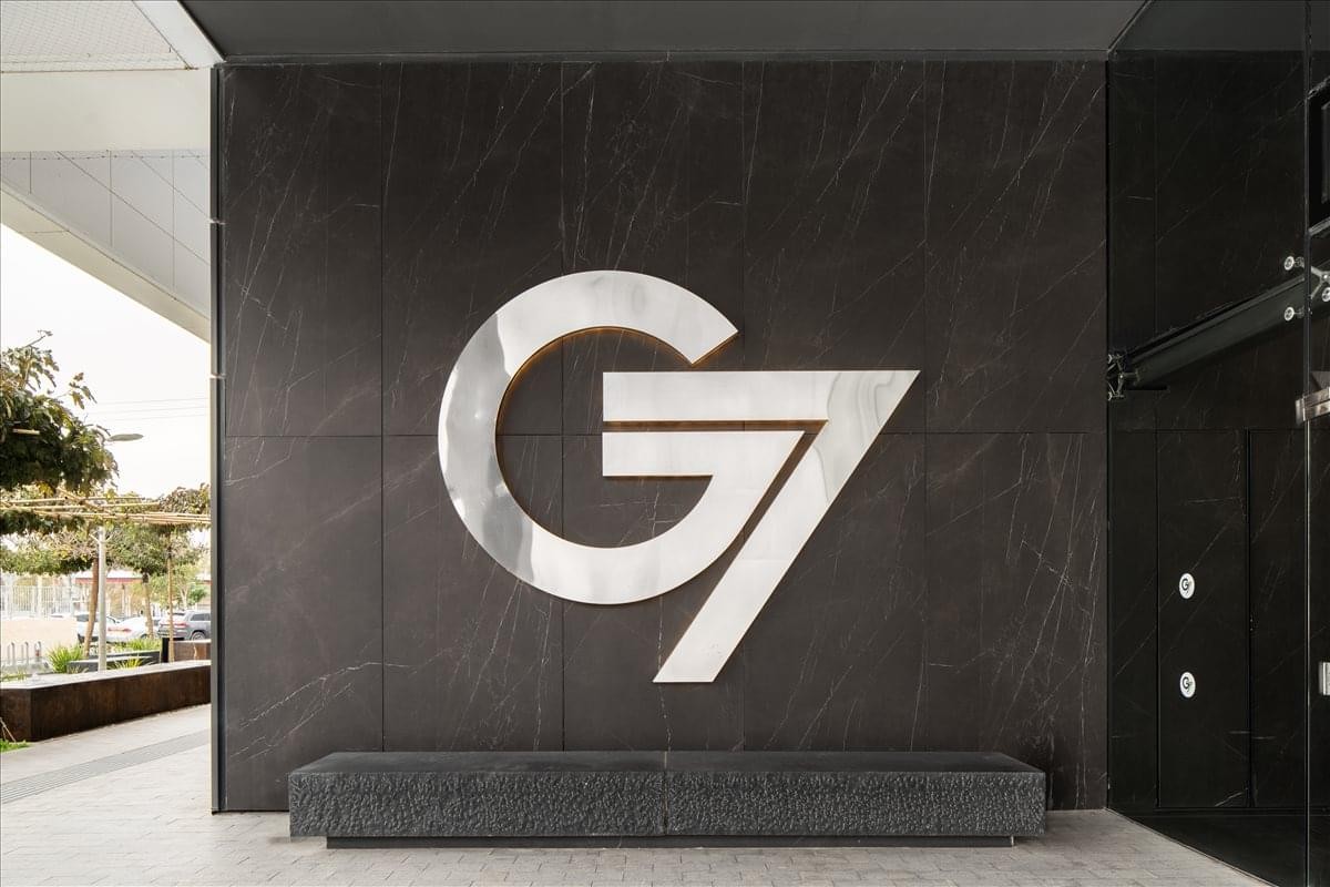 Large silver G7 Building logo mounted on a dark textured exterior wall.