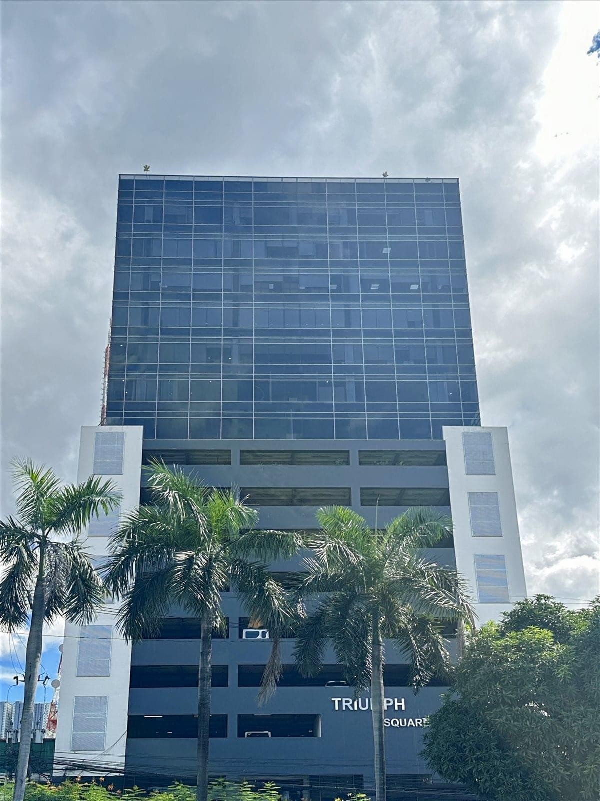 Exterior of Triumph Square Building with a glass facade and surrounding palm trees.