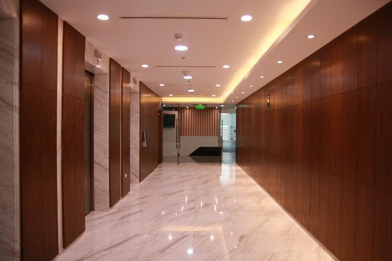 Warmly lit lobby of 1630, 3rd Avenue, Taguig featuring marble floors and wood paneled walls.