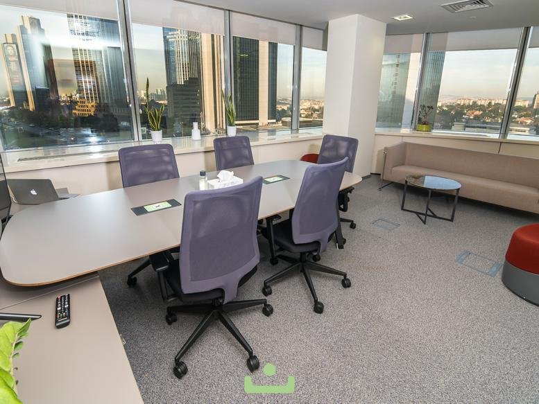 Executive boardroom with grey ergonomic chairs and a large wooden table overlooking the city.