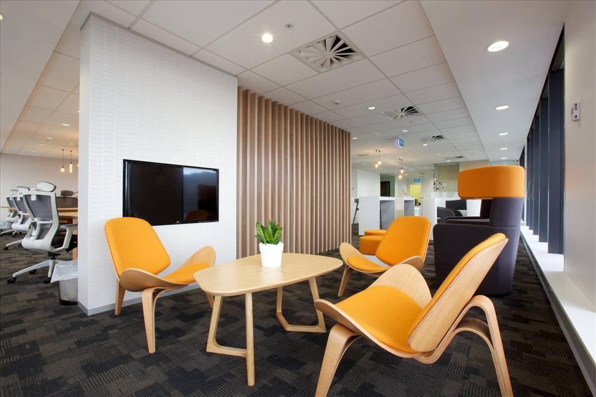 Lounge area with vibrant orange chairs and a wall-mounted television.