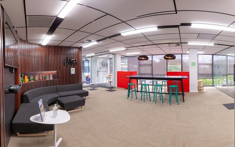 Common area at 27, Gillies Avenue, Auckland featuring curved grey seating and a high table with green stools.