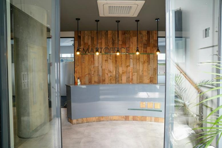 Reception area at Smart Office featuring a sleek grey desk and warm wood wall paneling.