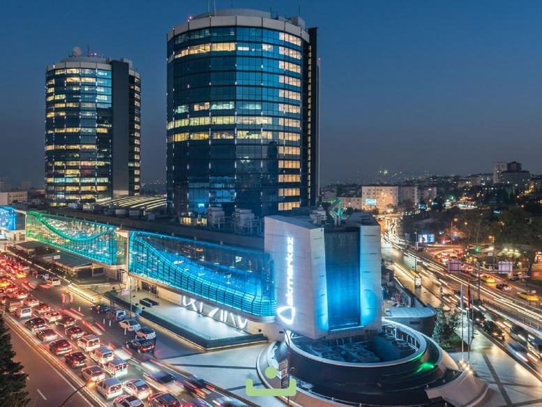 Exterior view of the glass-facade Nisbetiye Cd No 54 building amidst evening city traffic.