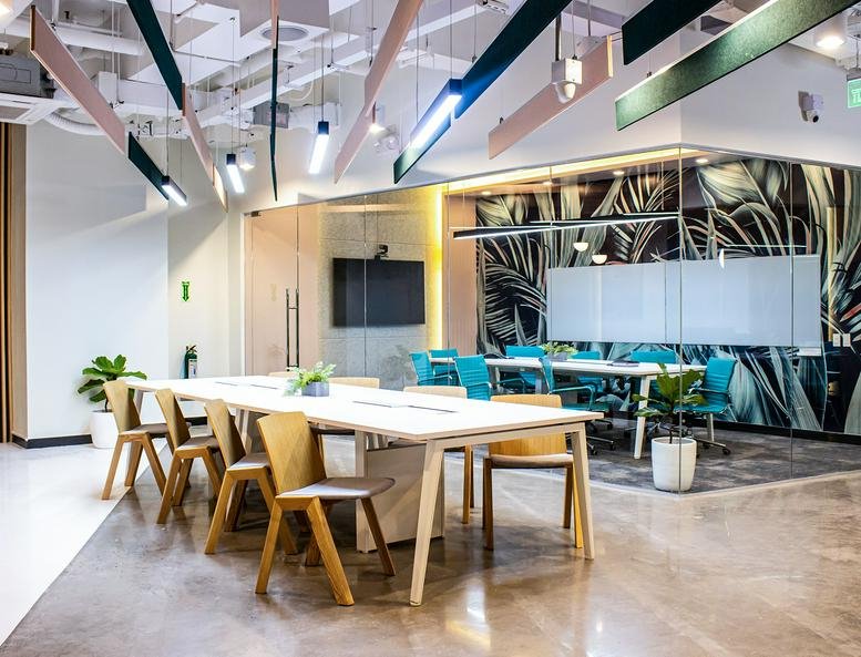 Spacious co-working area at Armstrong Corporate Center with long wooden tables and vibrant blue chairs.