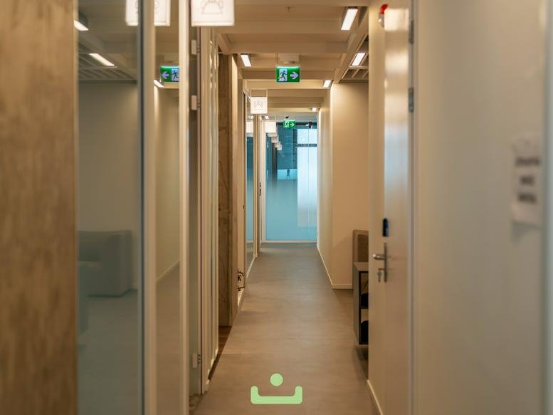 Brightly lit office corridor with wooden accents and glass doors.
