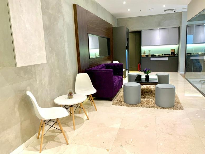 Spacious lounge area at The Prominence Alam Sutera Level 28 with a purple velvet sofa and modern white chairs.