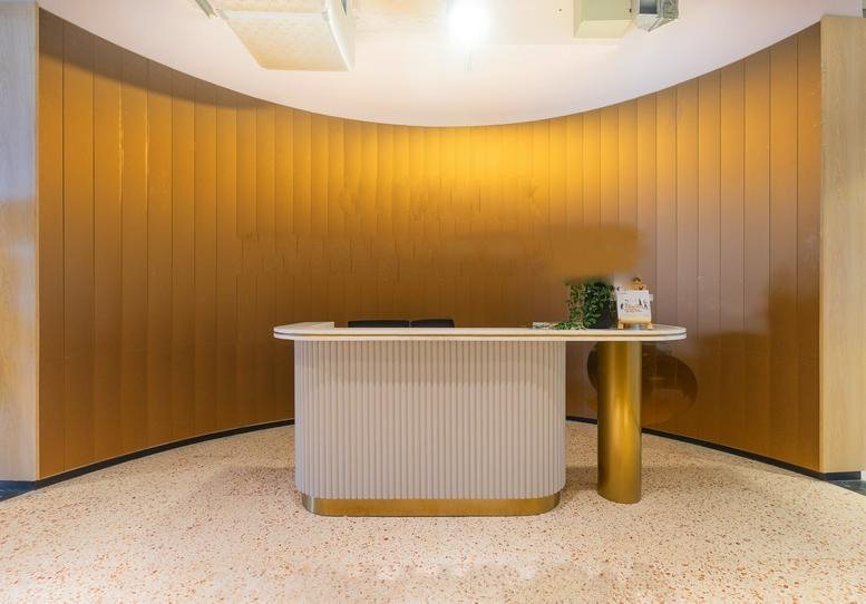 Reception area at ASG Tower with a curved wood-paneled wall and a white fluted desk with gold accents.
