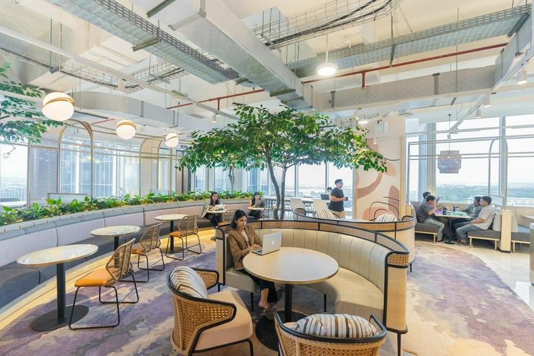 Lounge area featuring a central indoor tree, circular booths, and modern cafe seating.