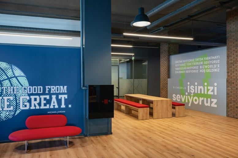 Vibrant lounge area with a red sofa, wooden tables, and motivational wall graphics.