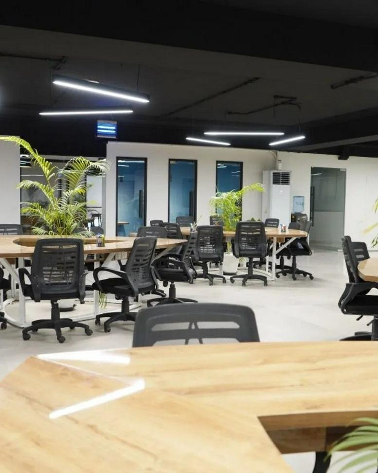 Modern open-plan workspace with wooden desks and indoor plants at Fortune Tower.