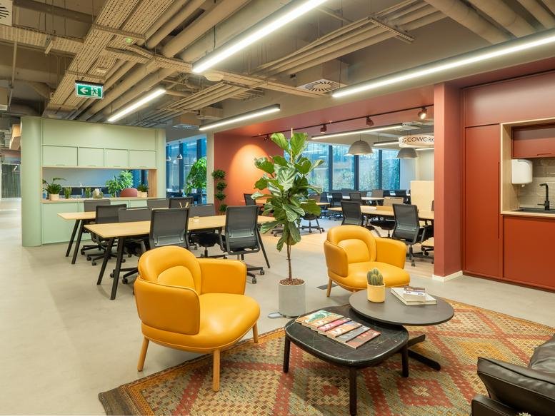 Open-plan coworking area at Nida Kule No: 7 with warm lighting and plush leather armchairs.