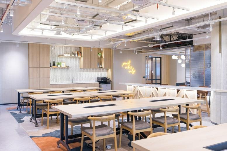 Spacious co-working area at Green Office Park with long wooden tables and hanging plants.