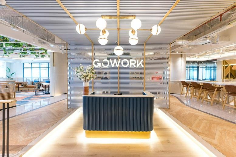 Bright reception area at Green Office Park, Tangerang featuring a blue desk and globe pendant lighting.