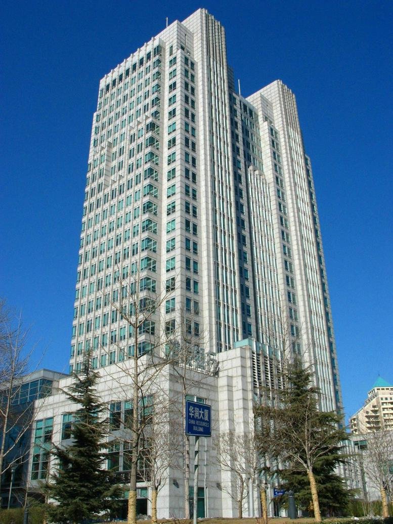 Exterior view of the towering white facade of the China Resources Building against a clear blue sky.