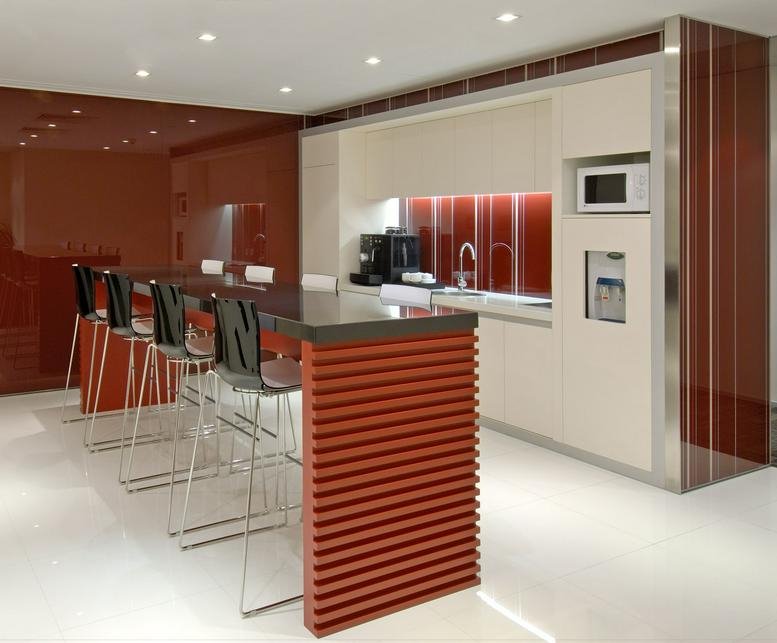 Modern communal kitchen and breakout area with a red slatted island and sleek white cabinetry.