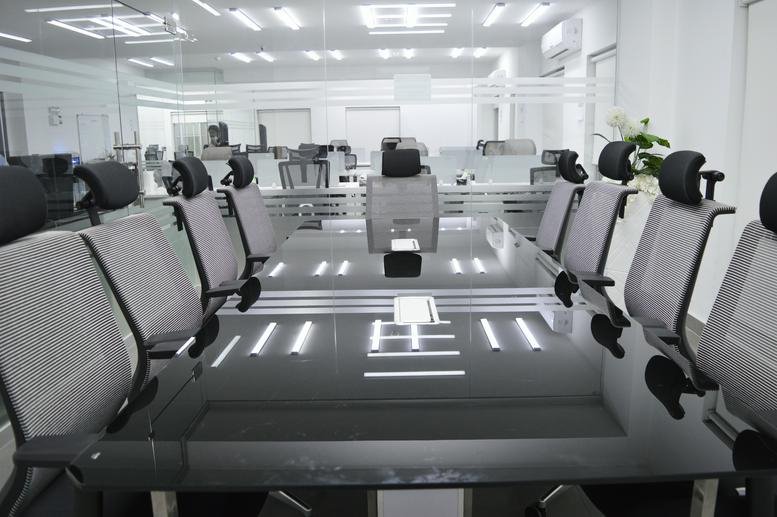 Modern conference room at Building No. 240C 3rd Floor, Lahore with a large black glass table and mesh chairs.