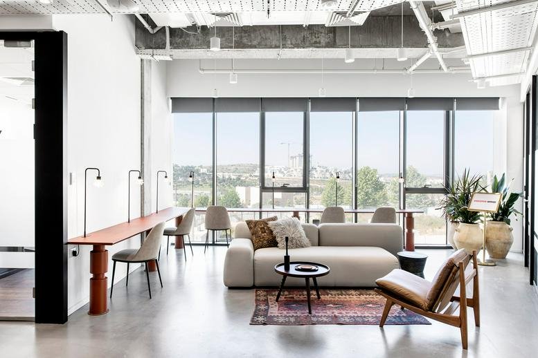 Spacious sunlit lounge at Dona 1, 38 Dam Hamaccabim Street with a large sofa and floor-to-ceiling windows.