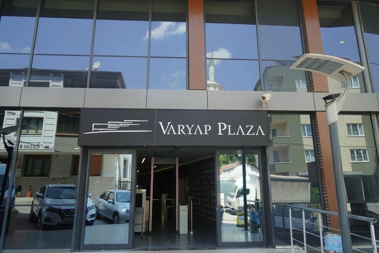 Exterior view of the modern glass and wood facade of the Varyap Plaza building entrance.