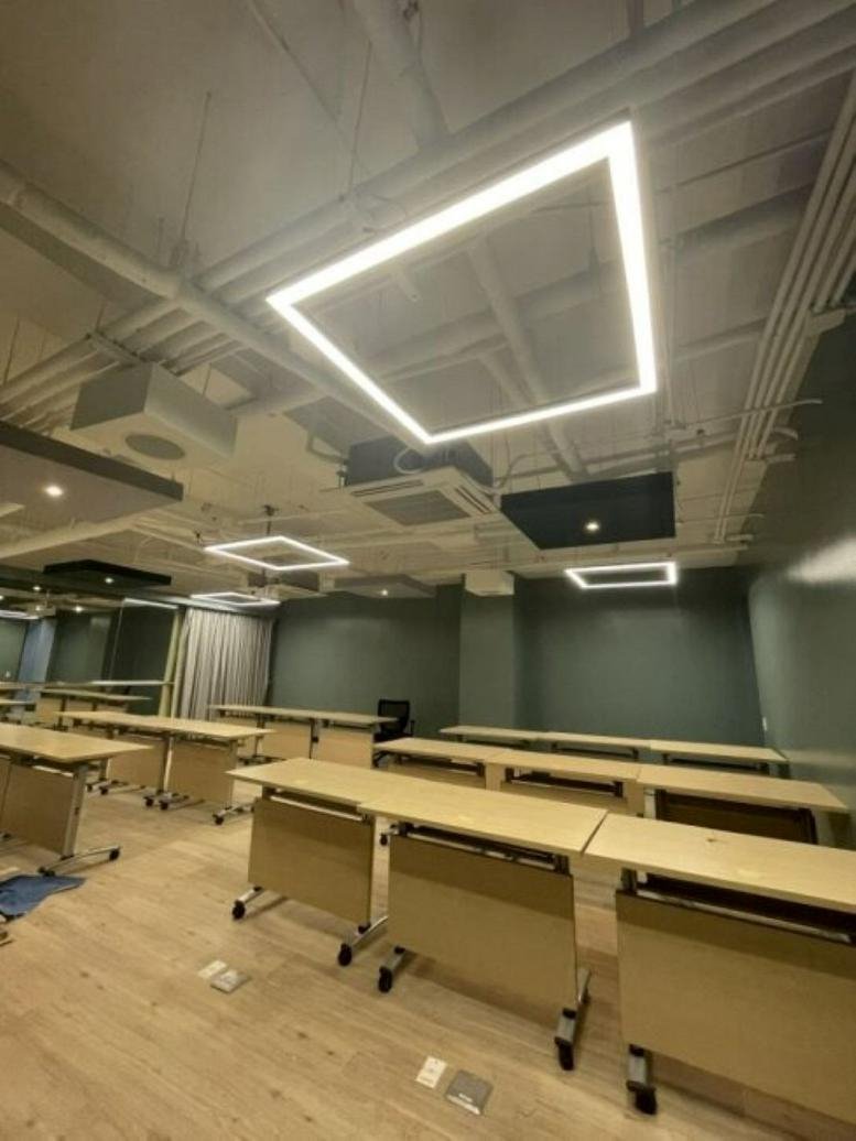 Open-concept training room at Five E-Com, Mall of Asia Complex featuring light wood desks and square LED lights.